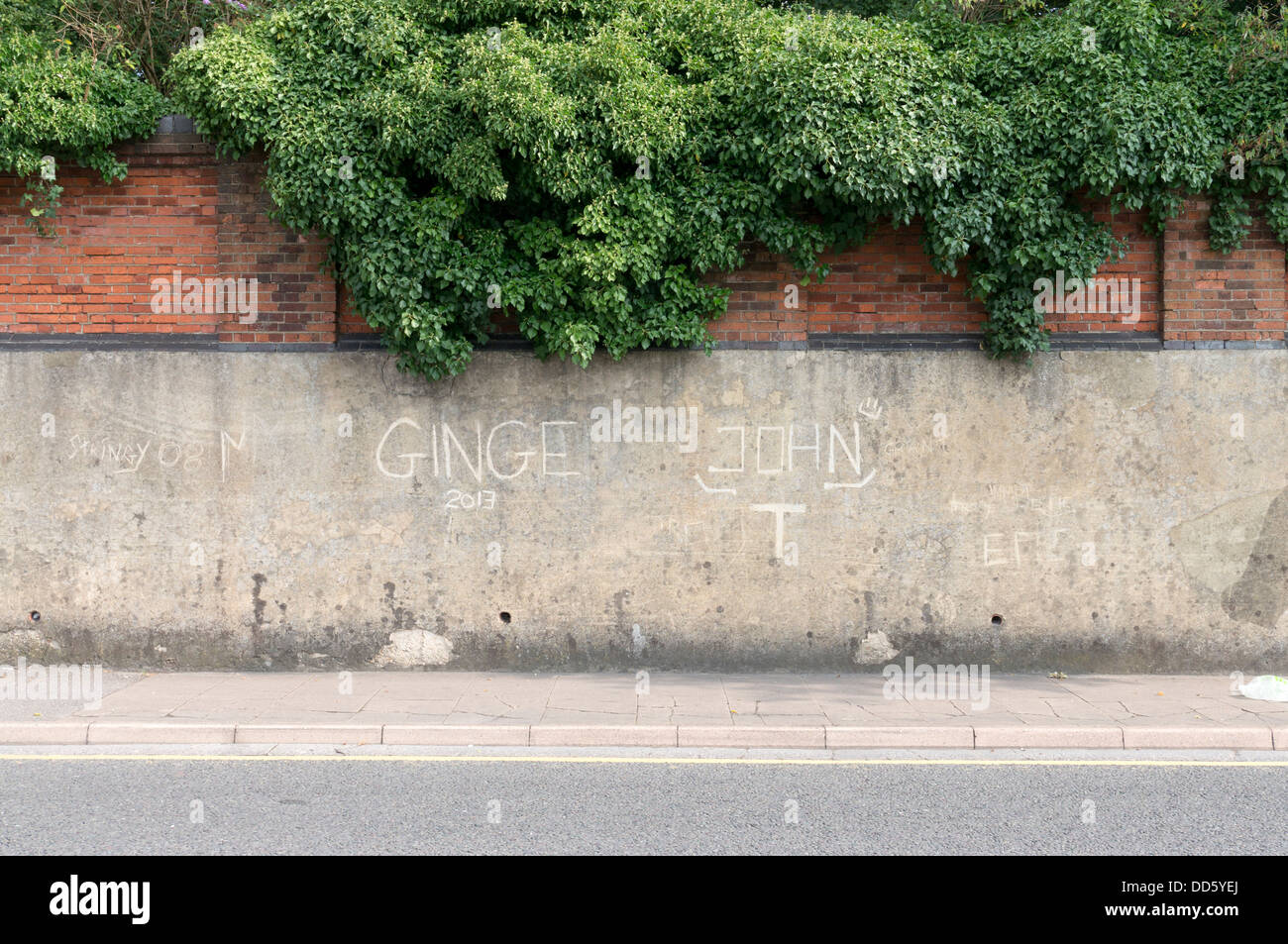 Graffiti scratched into concrete render wall Stock Photo