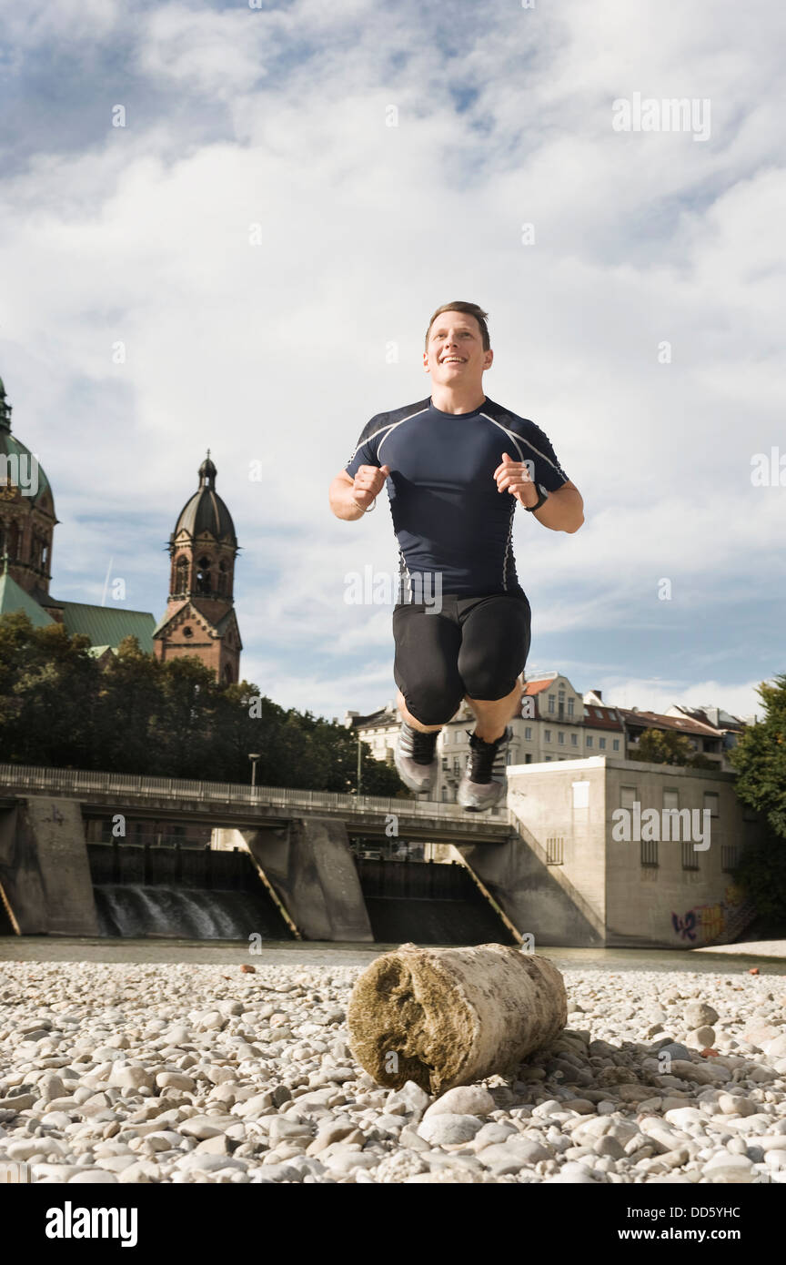 Young man jumping on the waterfront, Munich, Bavaria, Germany Stock Photo