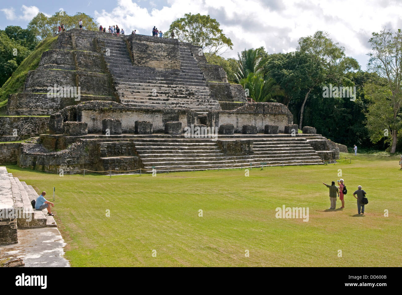 Belize, Central America, Altun Ha,Tourists in front and on top of the Temple of Masonry Altars in Plaza B of the Mayan ruins. Stock Photo