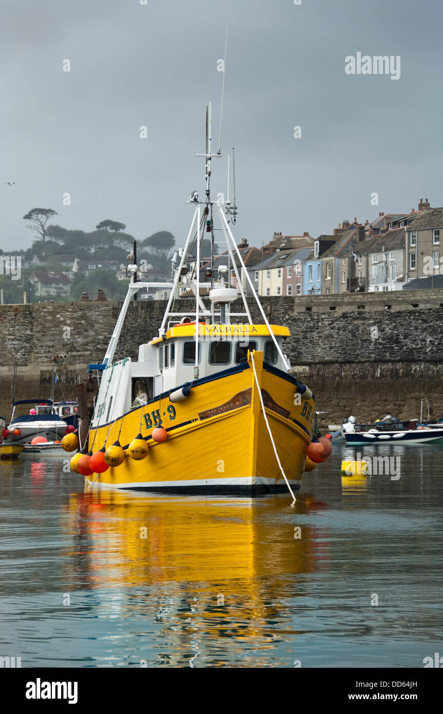 Vertical close up view of a small yellow fishing trawler in Mevagissey harbour. Stock Photo