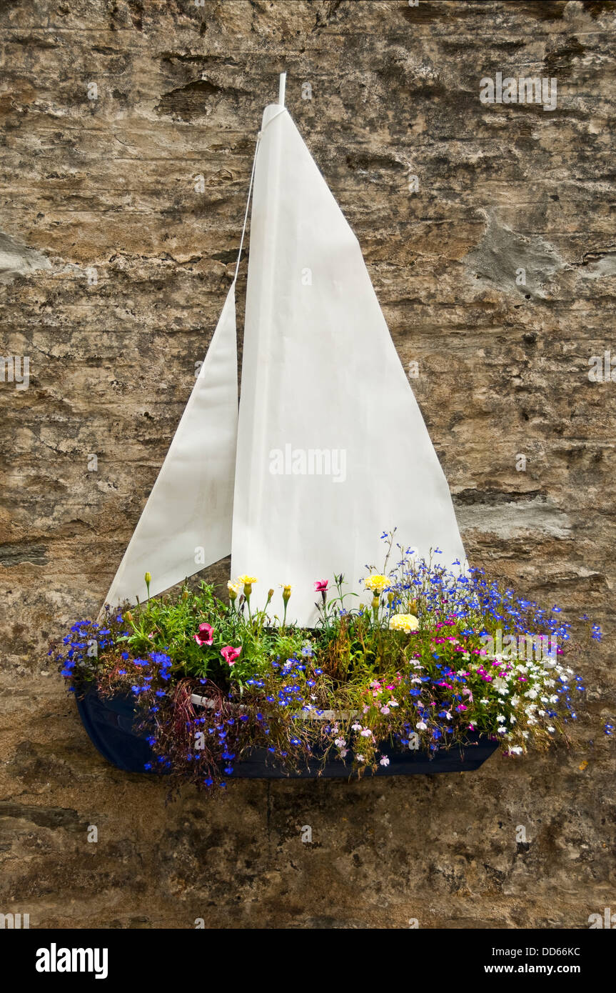 Vertical close up of an unusual boat shaped hanging basket with lots of bright flowers Stock
