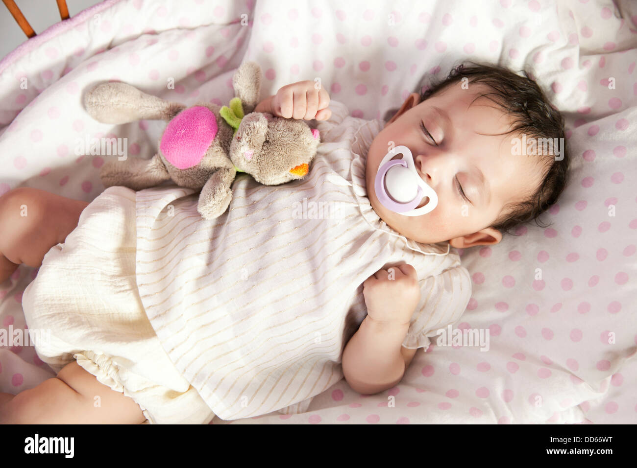Baby girl sleeping in wicker crib with toy Stock Photo Alamy