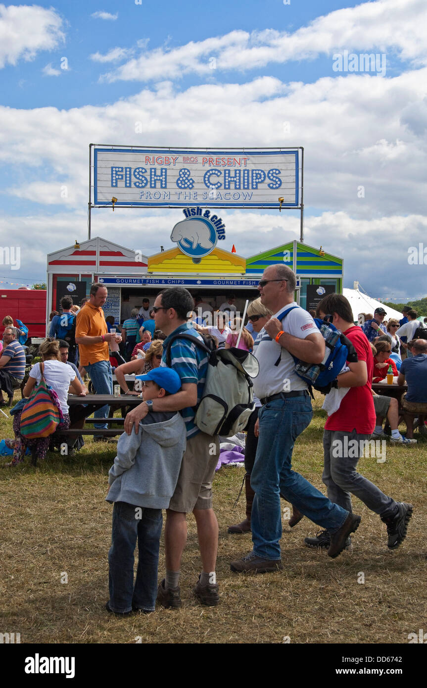 Vertical view of people standing by a fish and chip stall at a festival in the sunshine. Stock Photo