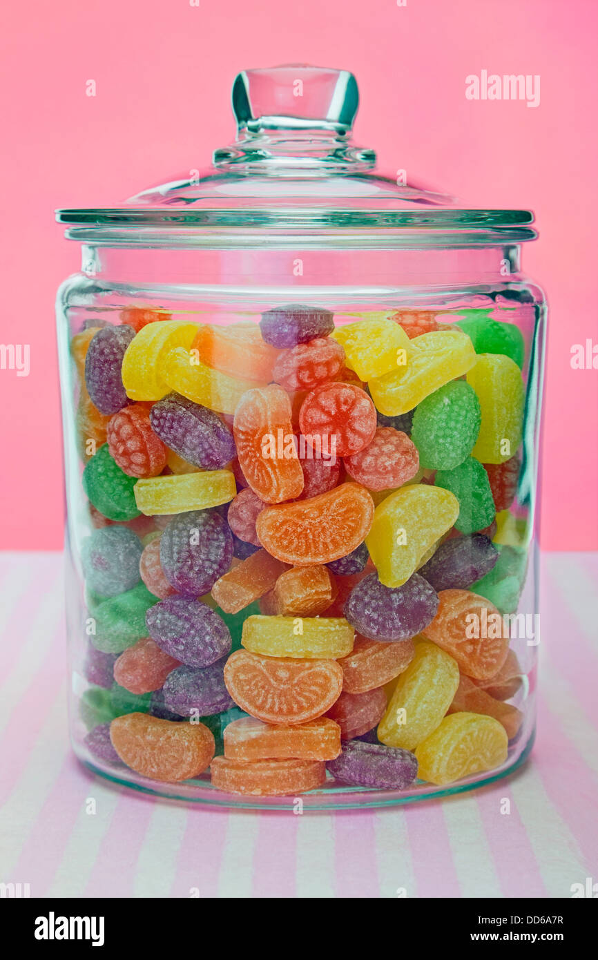 Sweets in a glass jar with a pink and white striped background Stock Photo