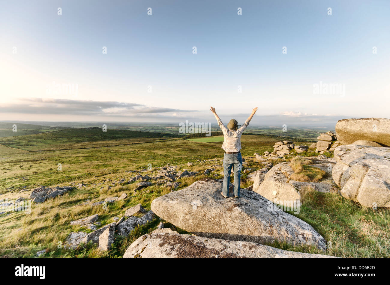 Vintage woman standing on top of hill with arms outstreched and looking at view Stock Photo