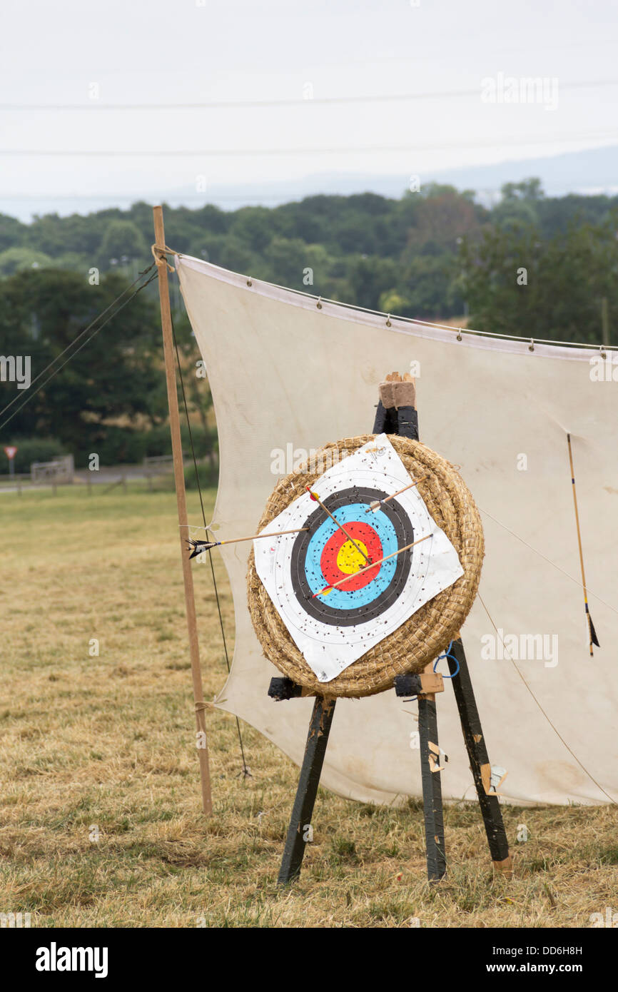 Archery target with several arrows sticking in it. The arrows are at odd angles due to being fired by inexperienced archers. Stock Photo