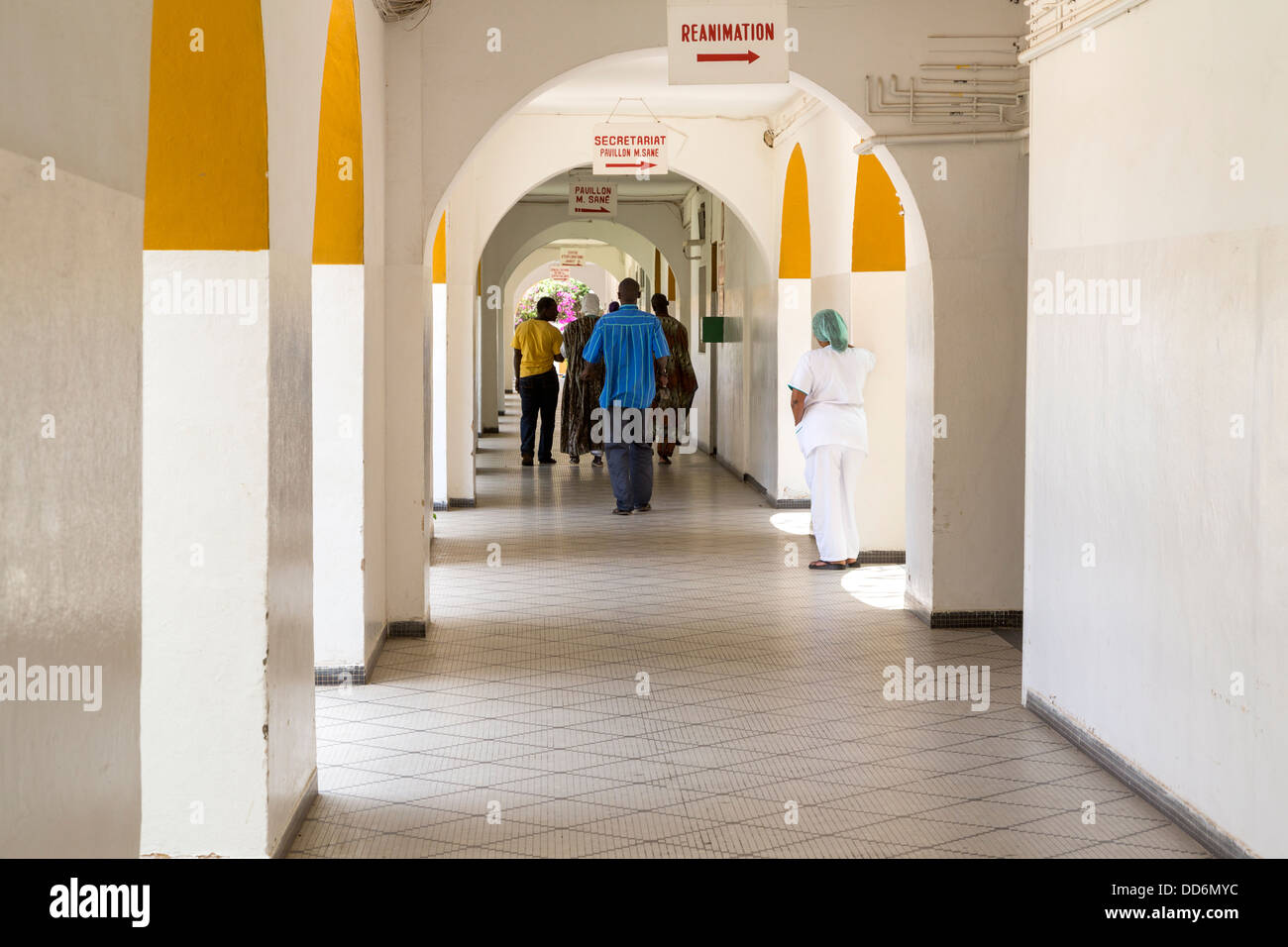 Dakar, Senegal. Dakar Hospital, Corridor and Receding Arches. Nurse Watching Family Members Depart. Stock Photo
