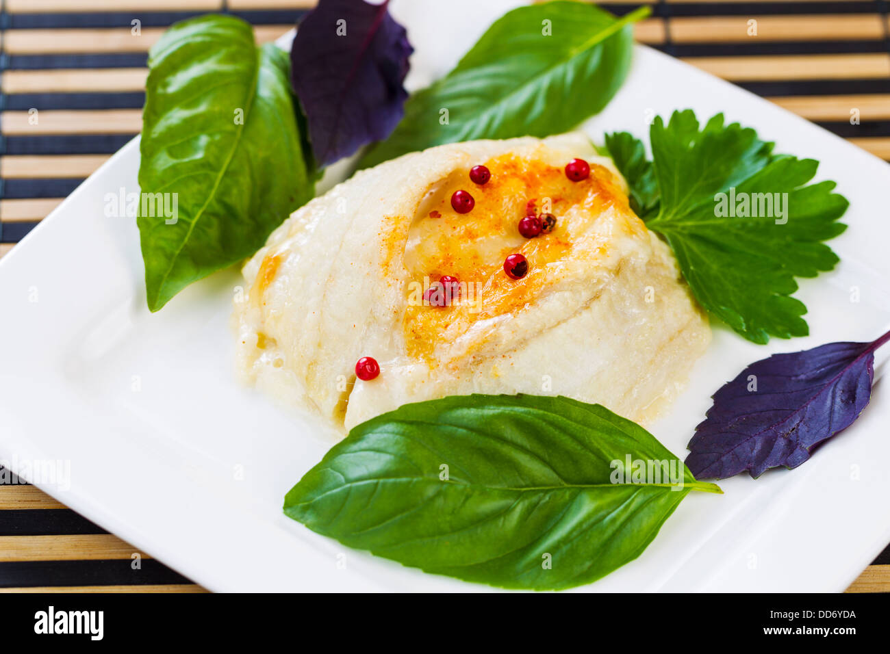 Closeup horizontal photo of baked stuffed sole fish, red peppercorn