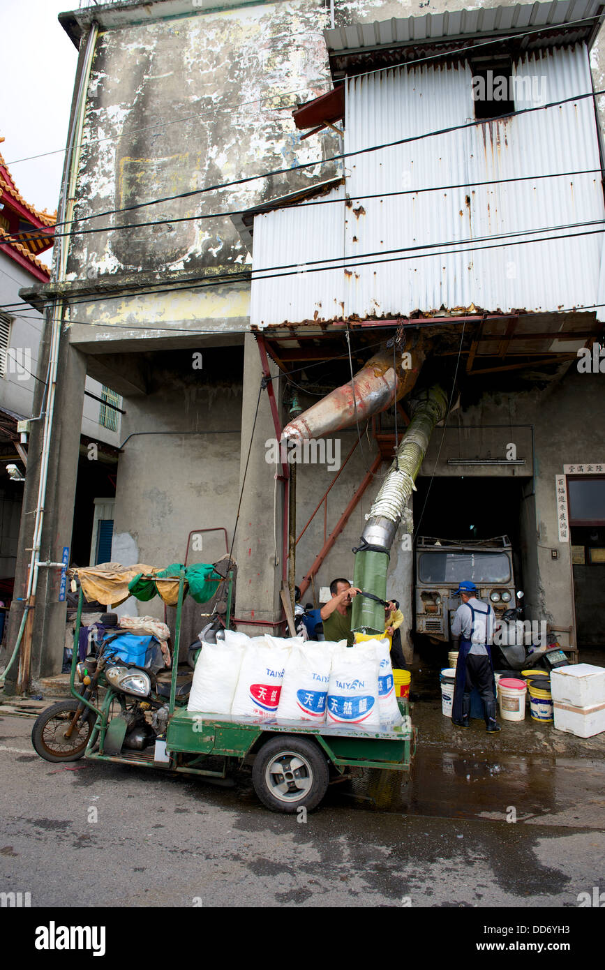 An ice factory with a small delivery truck loading ice for delivery Stock Photo