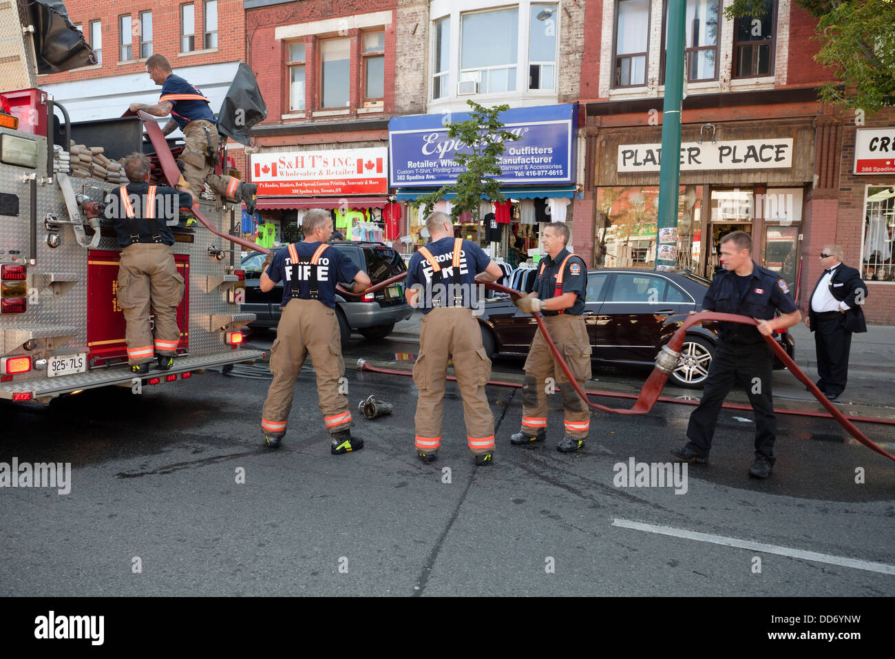 Toronto firefighters putting away a fire hose after a fire on Spadina Avenue, Toronto, Ontario, Canada. Stock Photo