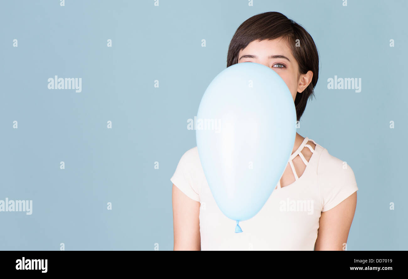 Beautiful young multiracial woman celebrating and playing with blue balloon Stock Photo