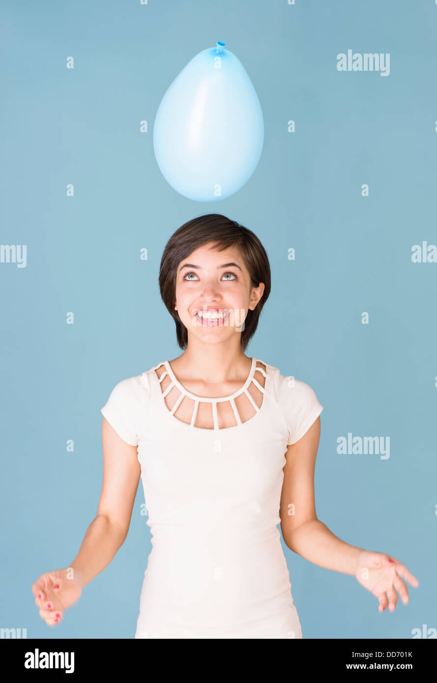 Beautiful young multiracial woman having fun with blue balloon at celebration Stock Photo