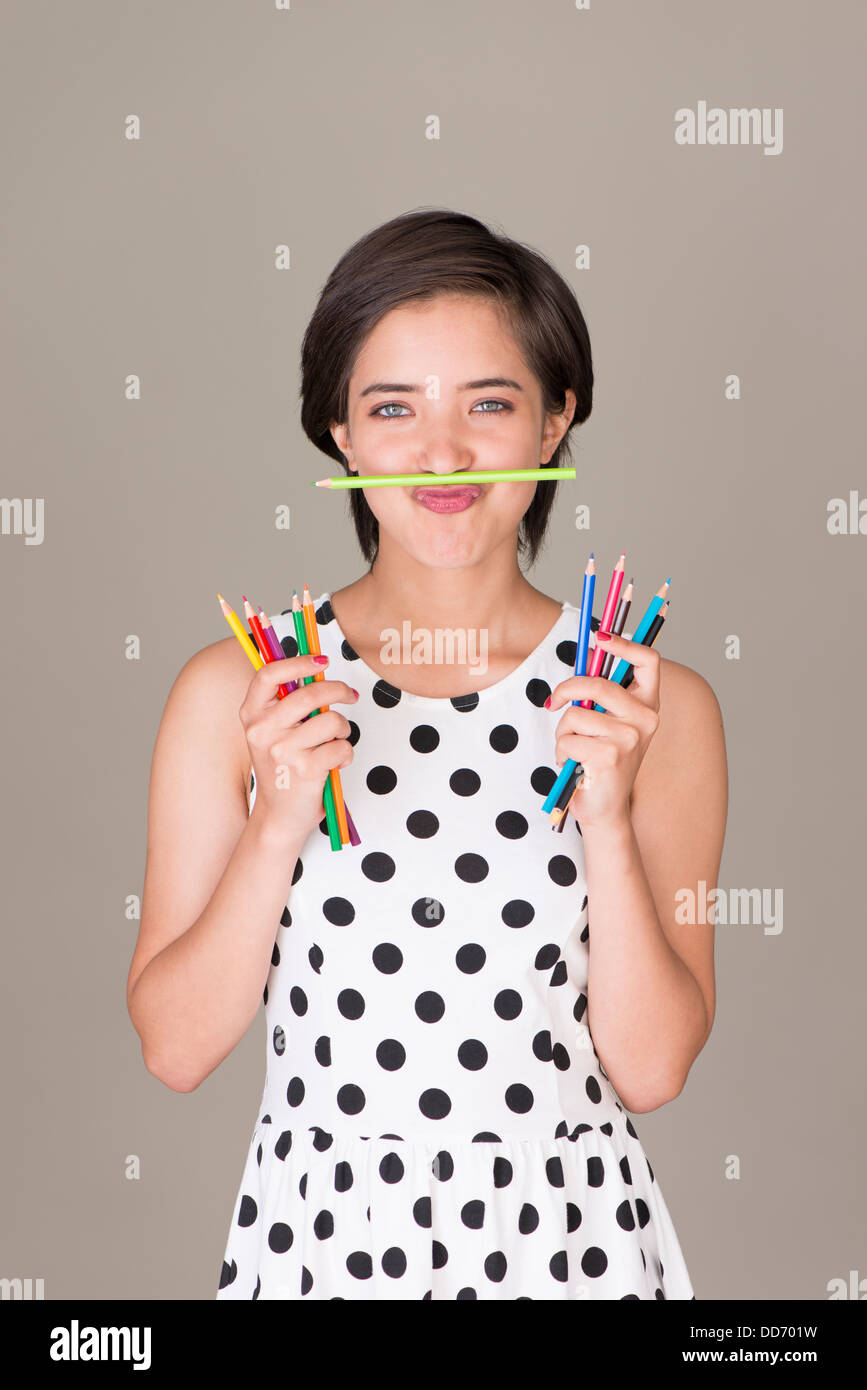 Beautiful young multiracial woman having fun and showing a set of colored pencils Stock Photo