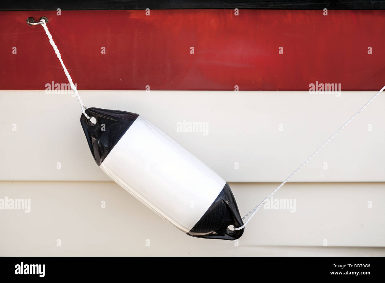 Small ship bump element hanging above white and red yacht hull Stock Photo