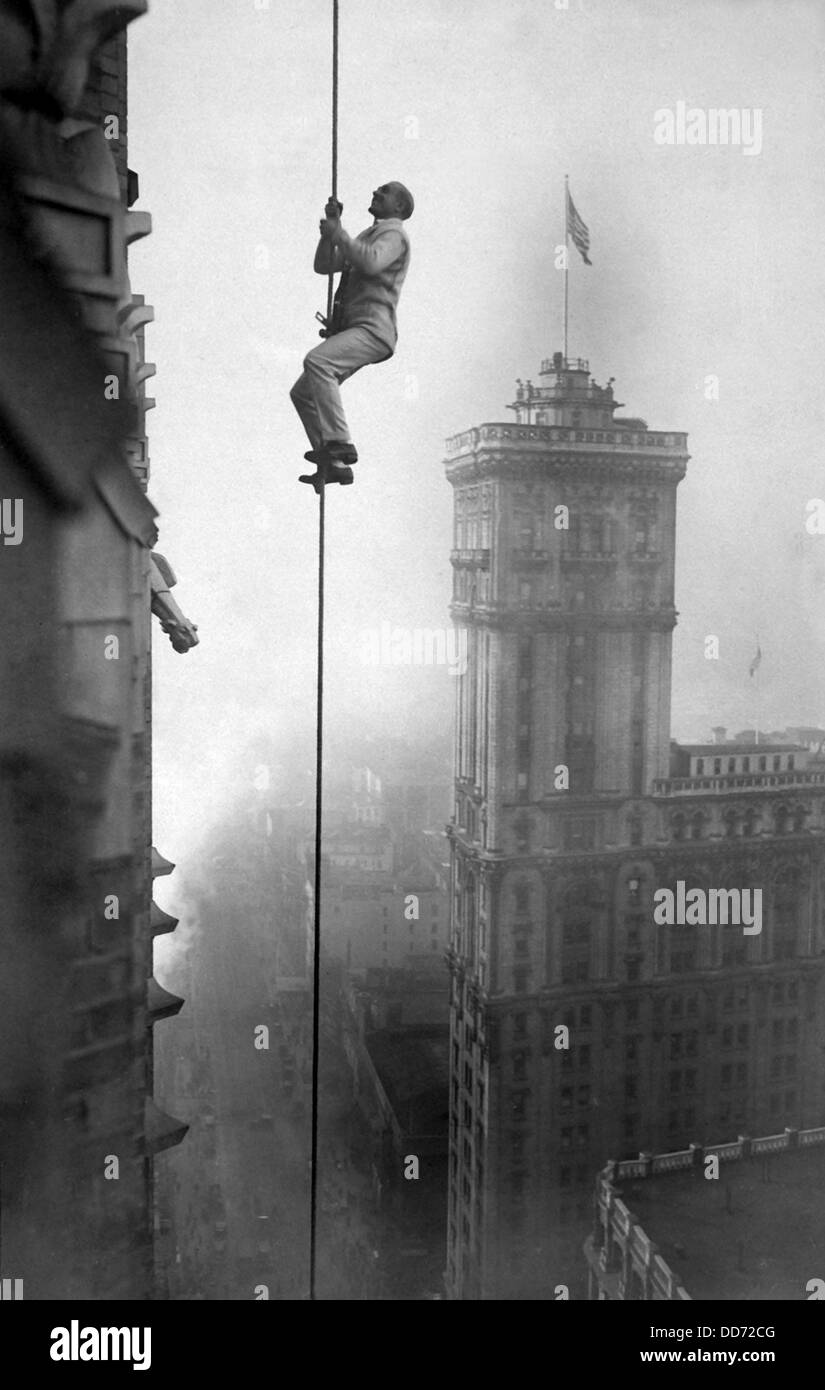 A man, identified as 'the human squirrel', climbing at a dizzy height above Times Square to promote War Relief Fund Stock Photo