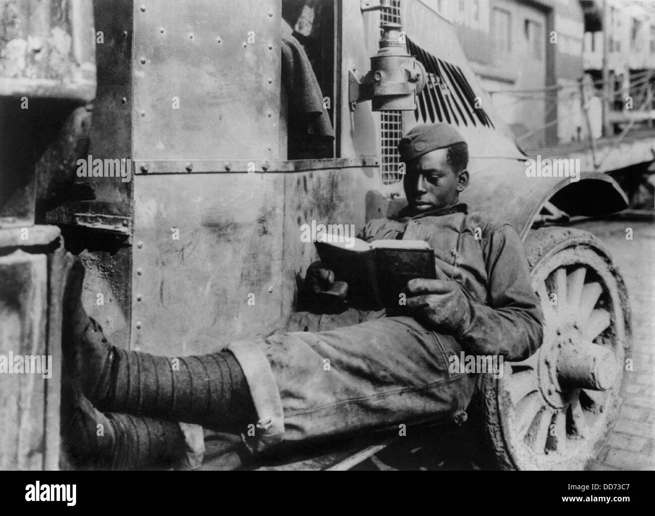 African American WW1 soldier reading book in France. 1919. He relaxes on the running board of a truck in St. Nazaire, France. Stock Photo