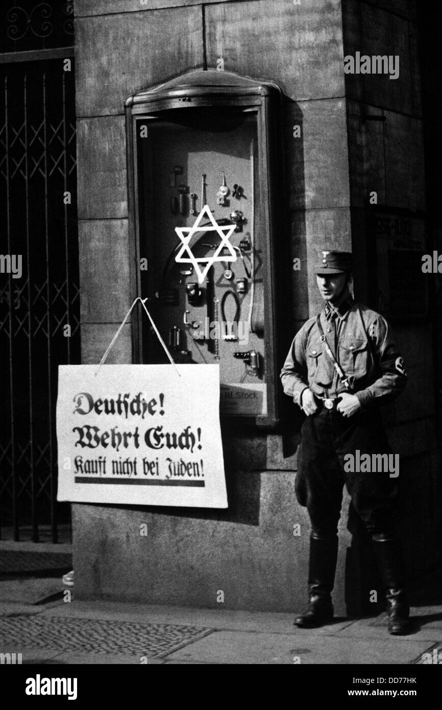 Anti-Semitic boycott in Berlin, Germany, April 1, 1933. A Nazi storm trooper stands beside a placard reading, 'Germans, defend Stock Photo