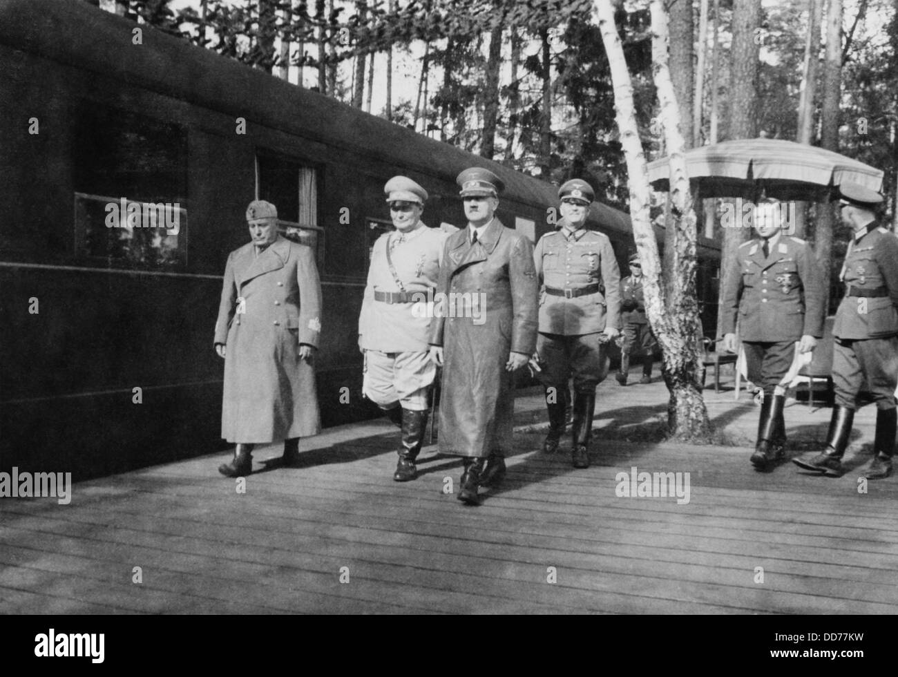 Adolf Hitler, Hermann Goering, and Benito Mussolini. They walk with other German military officers at railroad station, on Stock Photo