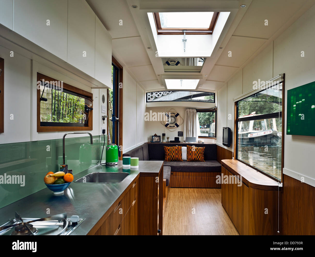 Narrowboat, London, United Kingdom. Architect: Pete Young, 2013. Interior towards seating/fold away bed with passing boat on the Stock Photo