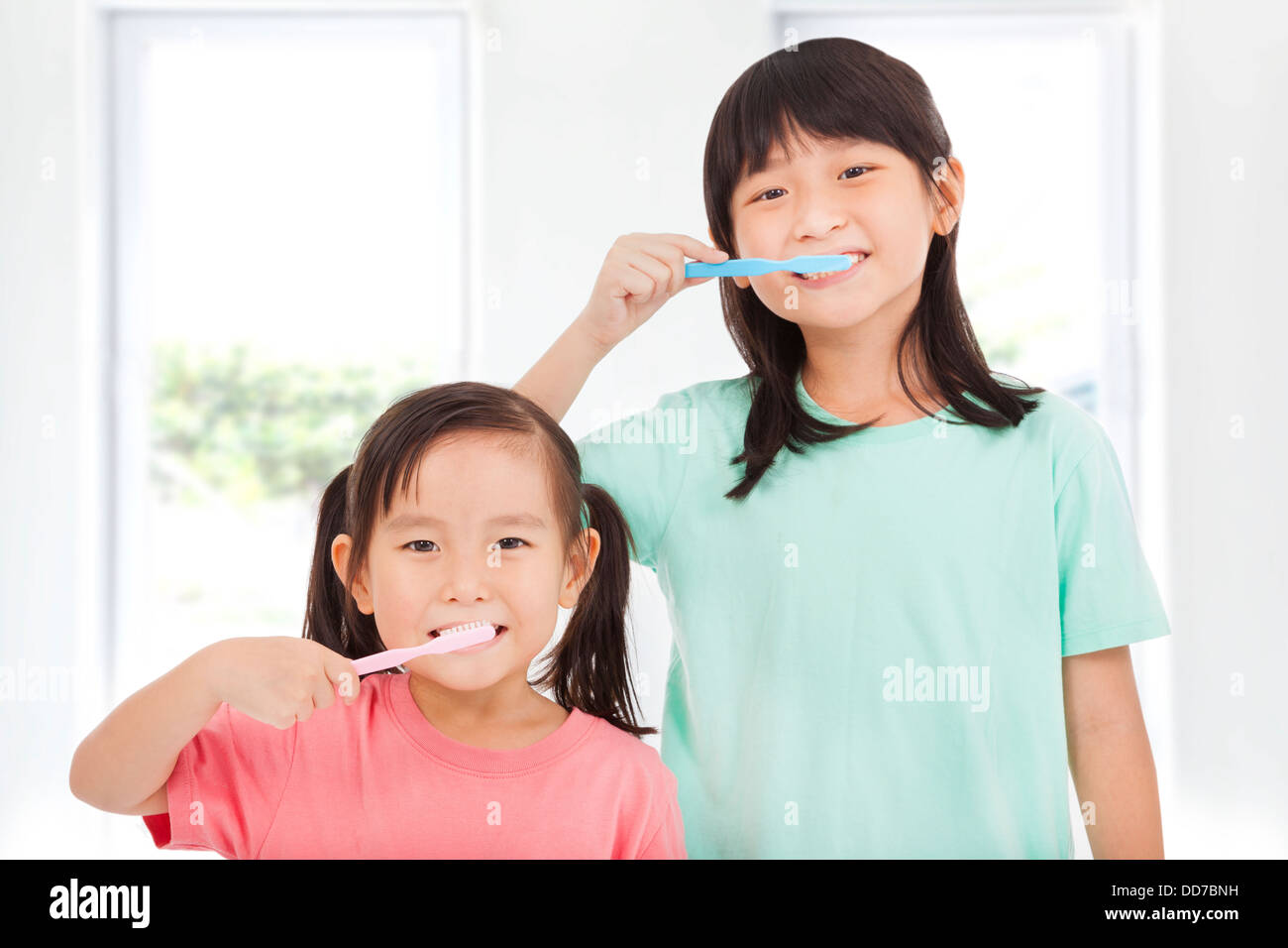 two happy little girls brushing her teeth Stock Photo
