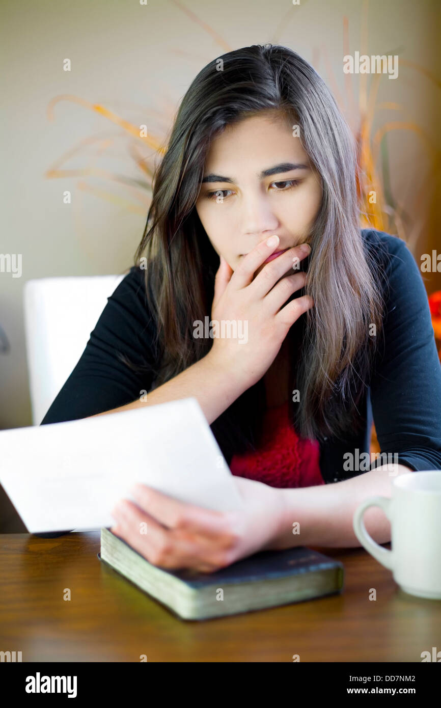 Teenage girl or young woman reading a note, worried expression Stock Photo