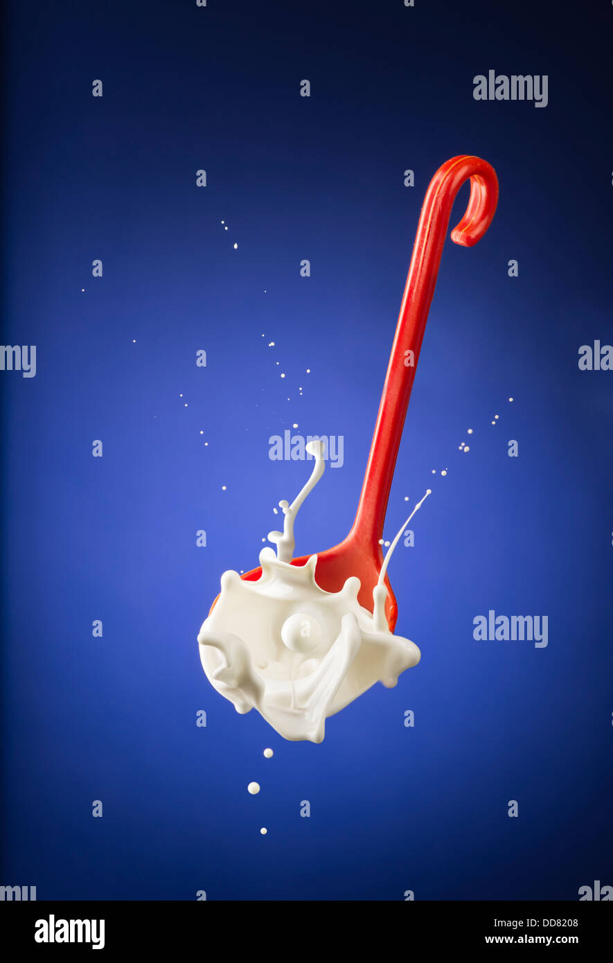 Milk Splashing Out Of Red Ladle Stock Photo