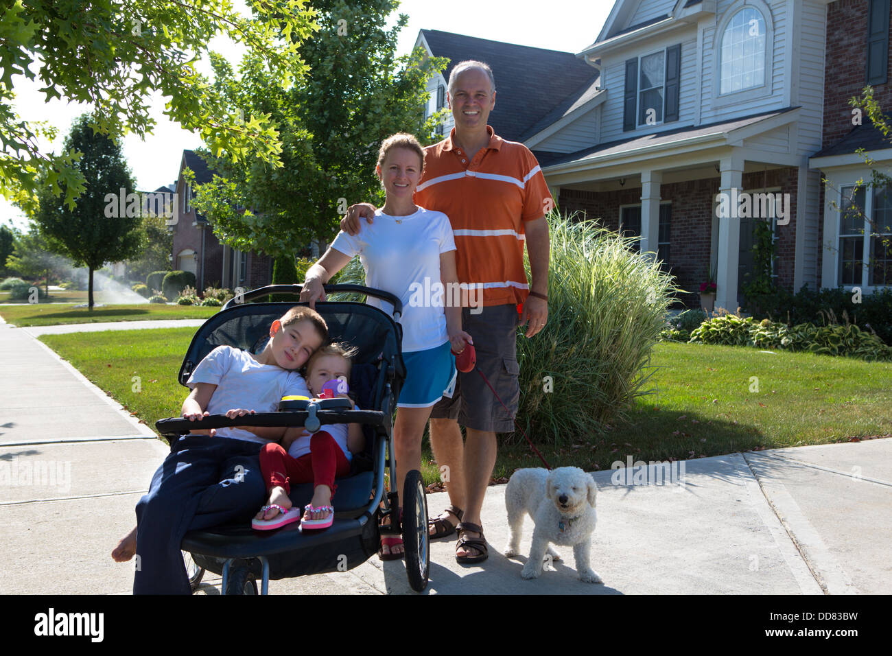 Family posing in the morning walk with their puppy dog infront of their house. Stock Photo