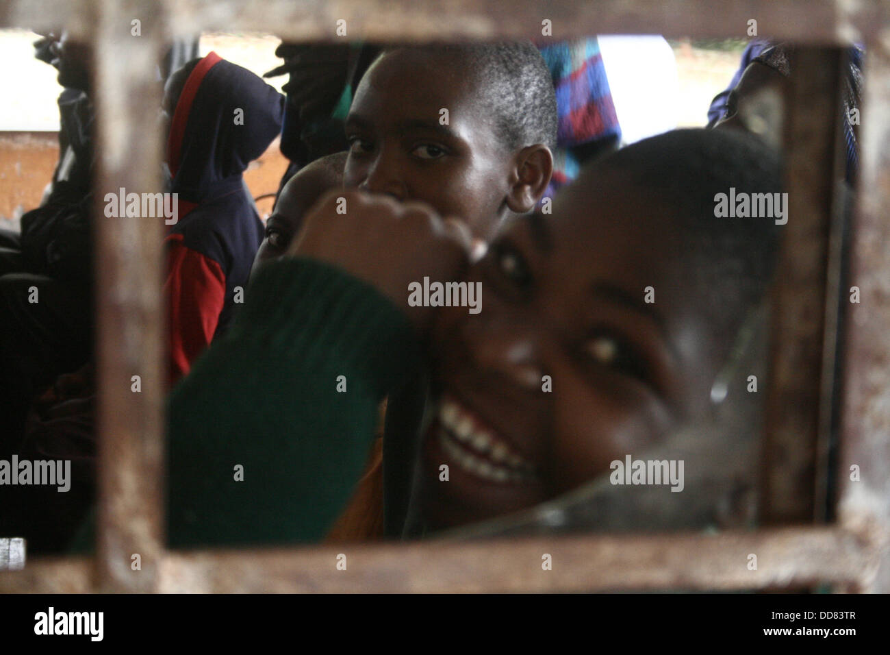 African schoolboys looking at photographer through a broken classroom window. Stock Photo