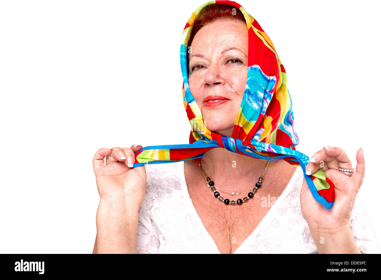 Old lady giving a happy proud look in her colorful headscarf, isolated on white Stock Photo