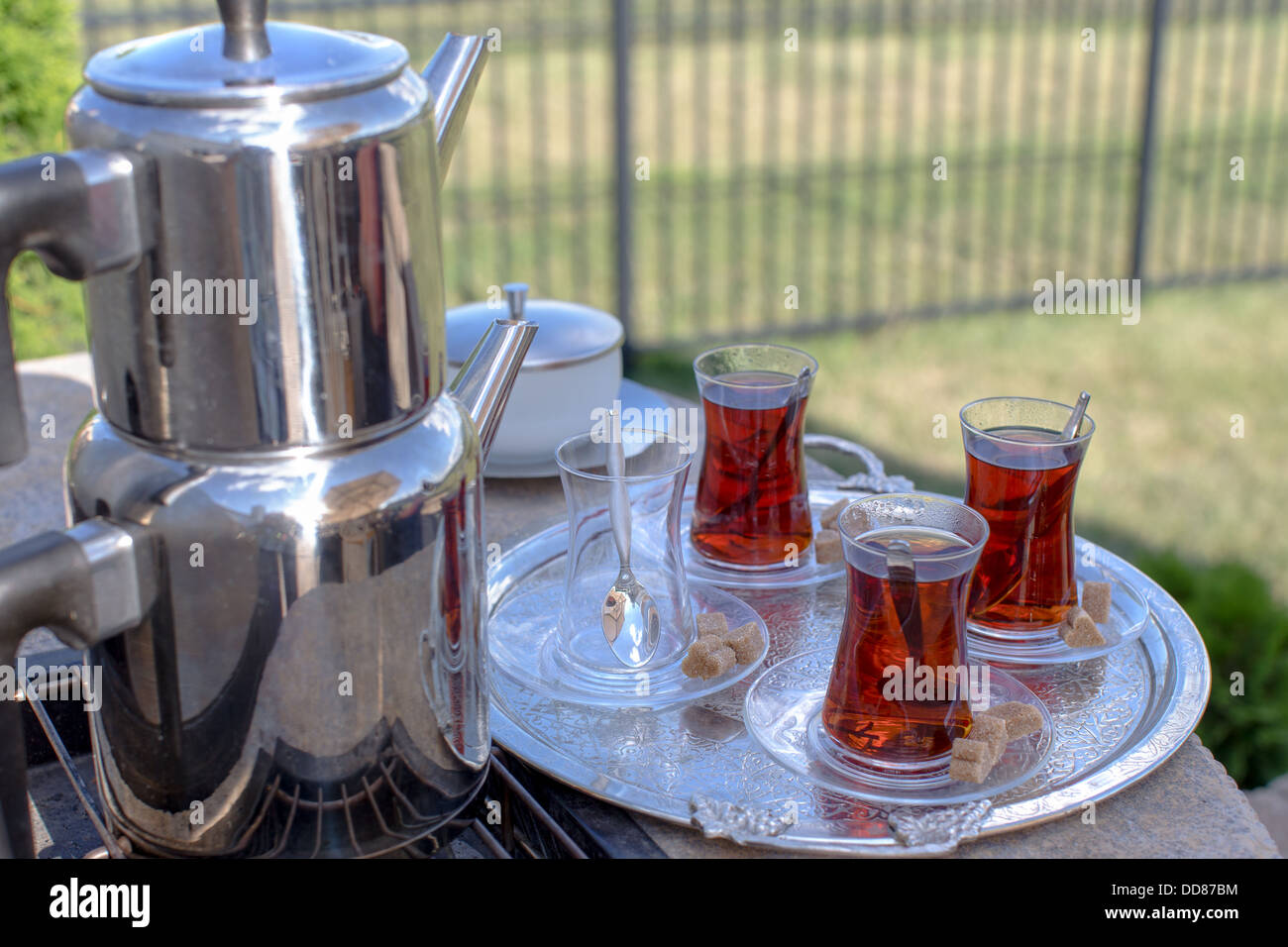 Traditional strong black Turkish tea served with contemporary kettle and glasses along with brown sugar Stock Photo
