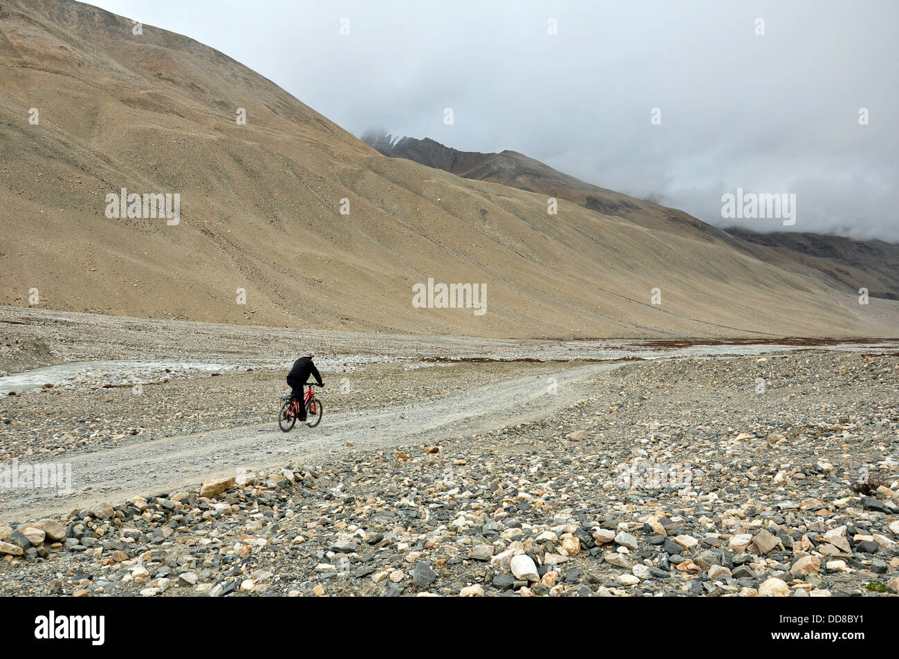 an old man is cycling along the track in the mount everest track in Tibet Stock Photo