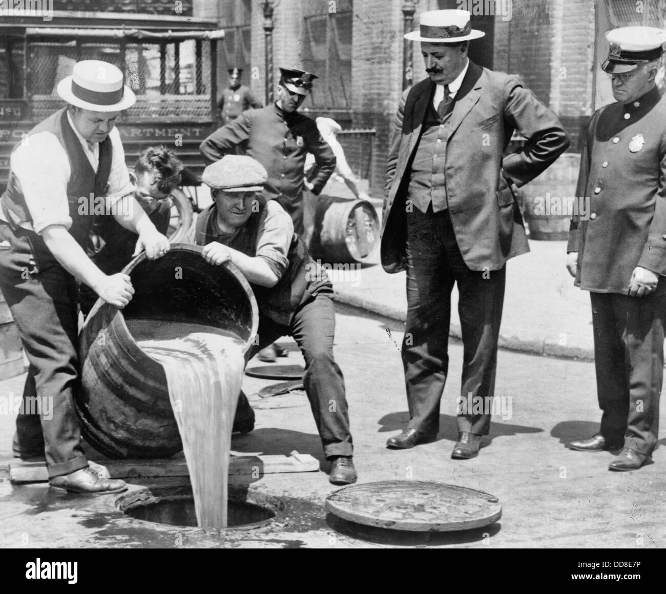New York City Deputy Police Commissioner John A. Leach, right, watching agents pour liquor into sewer following a raid during the height of prohibition, 1921 Stock Photo