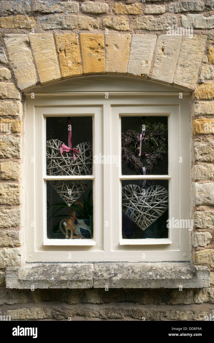 Craft Hearts in the window of a Cotswold country cottage. England Stock