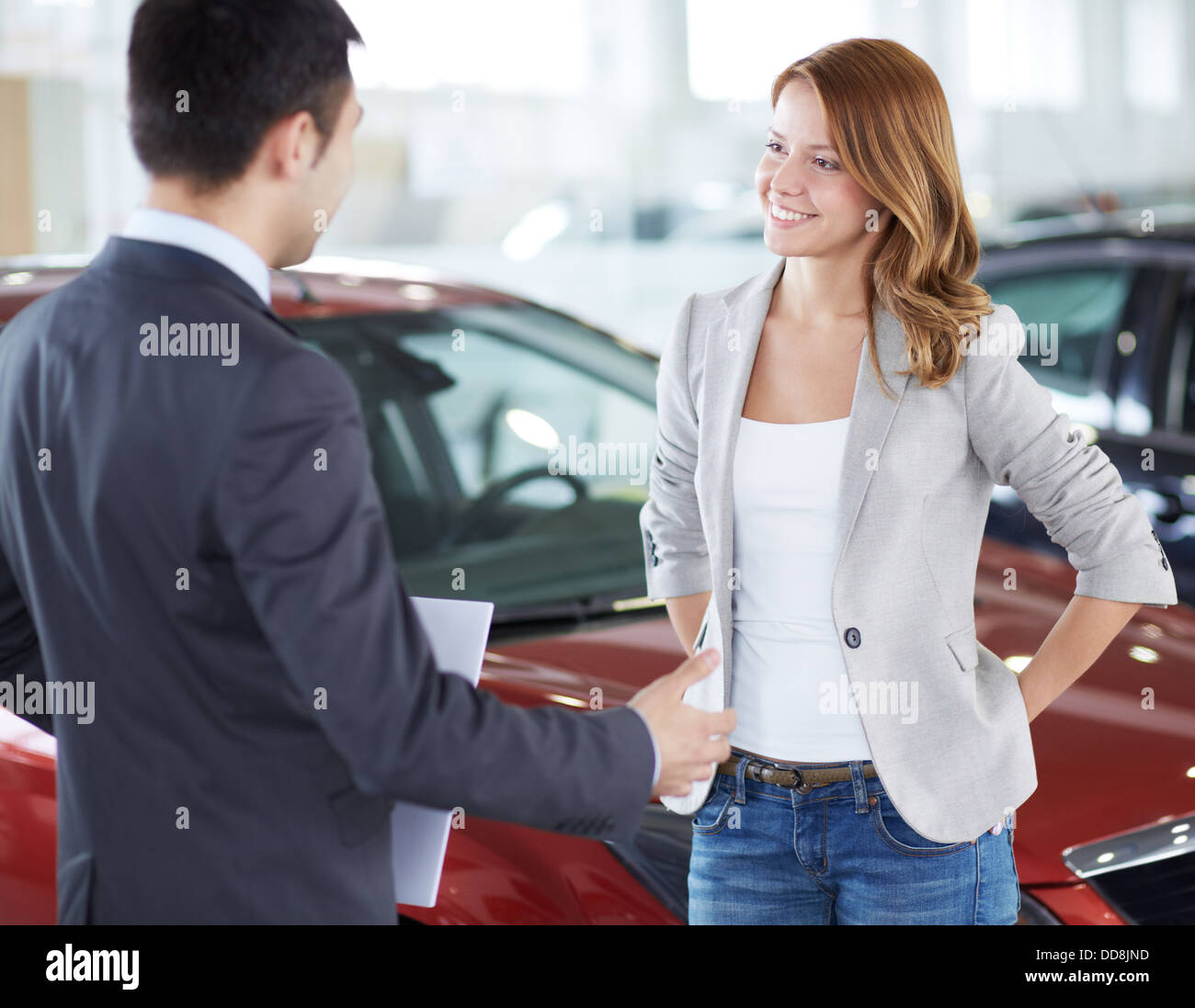 Successful young lady discussing her potential purchase with a car dealer Stock Photo