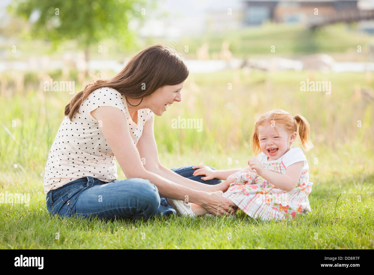 Caucasian mother and daughter playing in grass Stock Photo