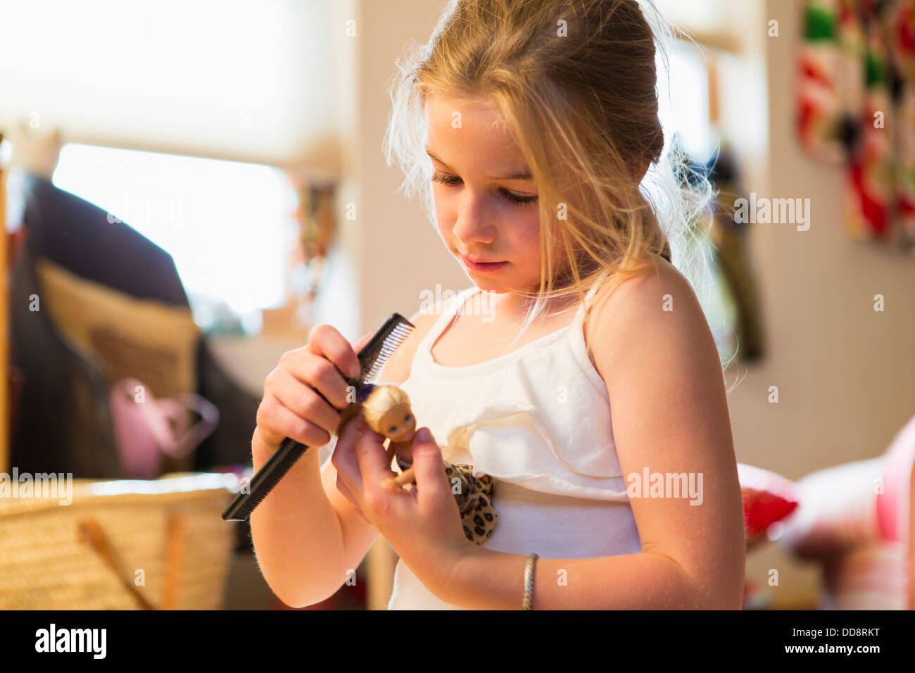 Caucasian girl combing doll's hair Stock Photo