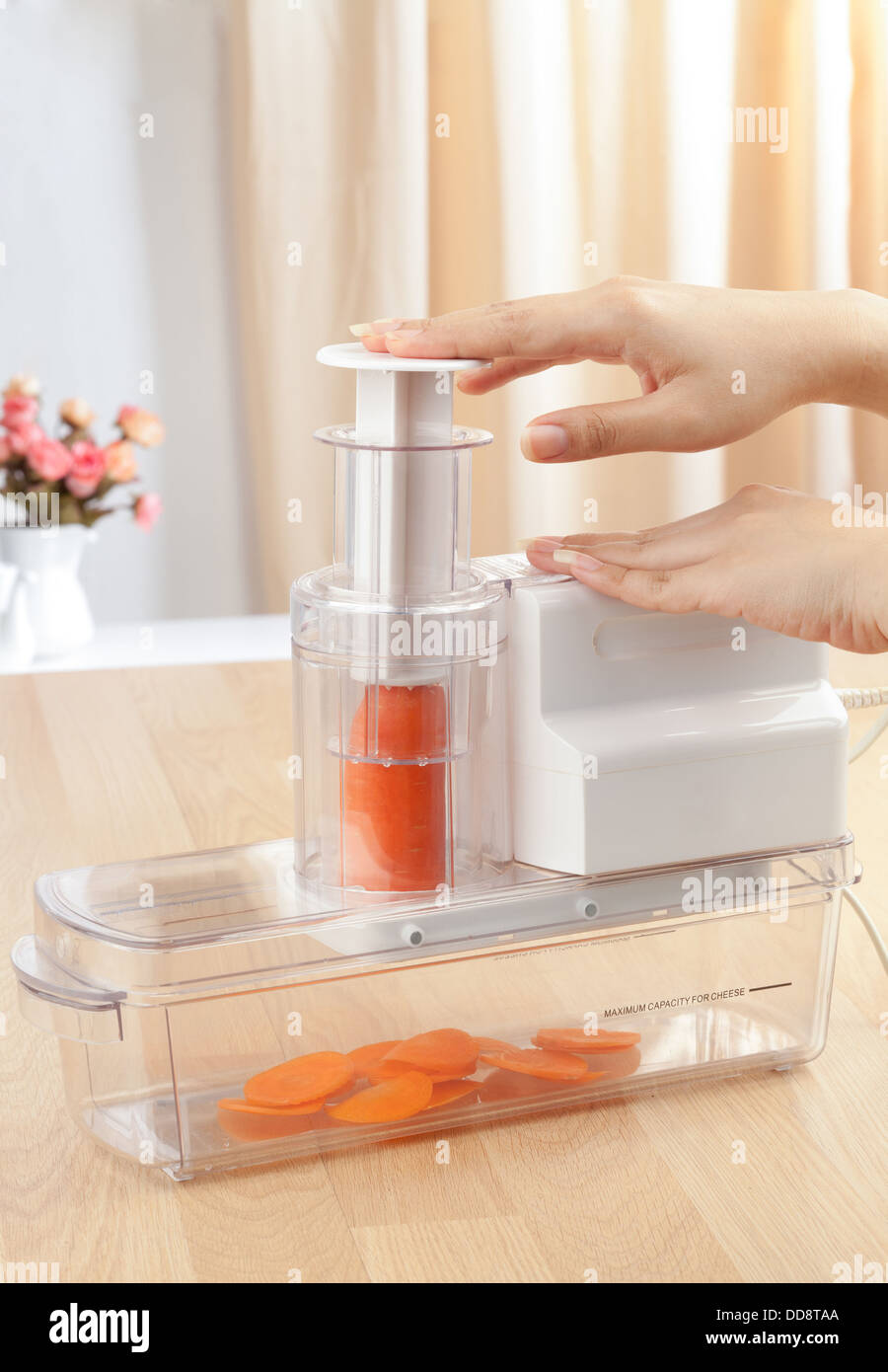 housewife's hands slicing carrot by electric slicer machine Stock Photo