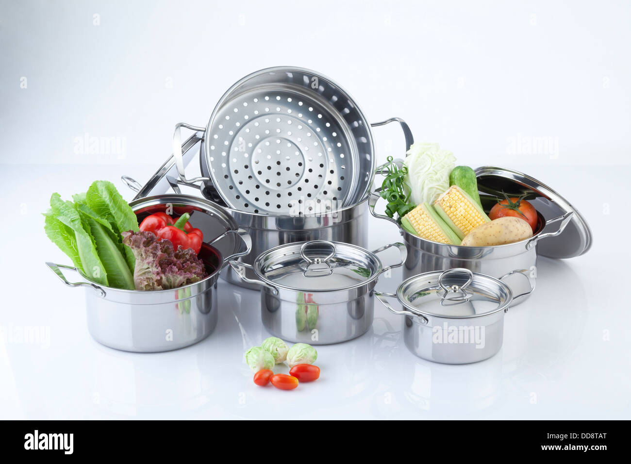 Set of stainless pots with lids and vegetable Stock Photo