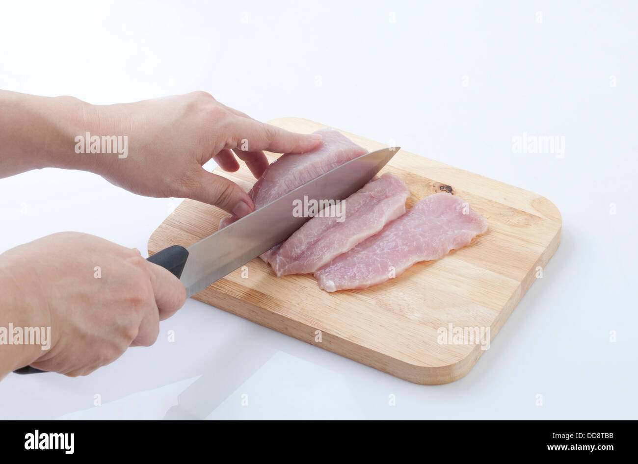 housewife cutting pork with knife on a wooden cutting board Stock Photo