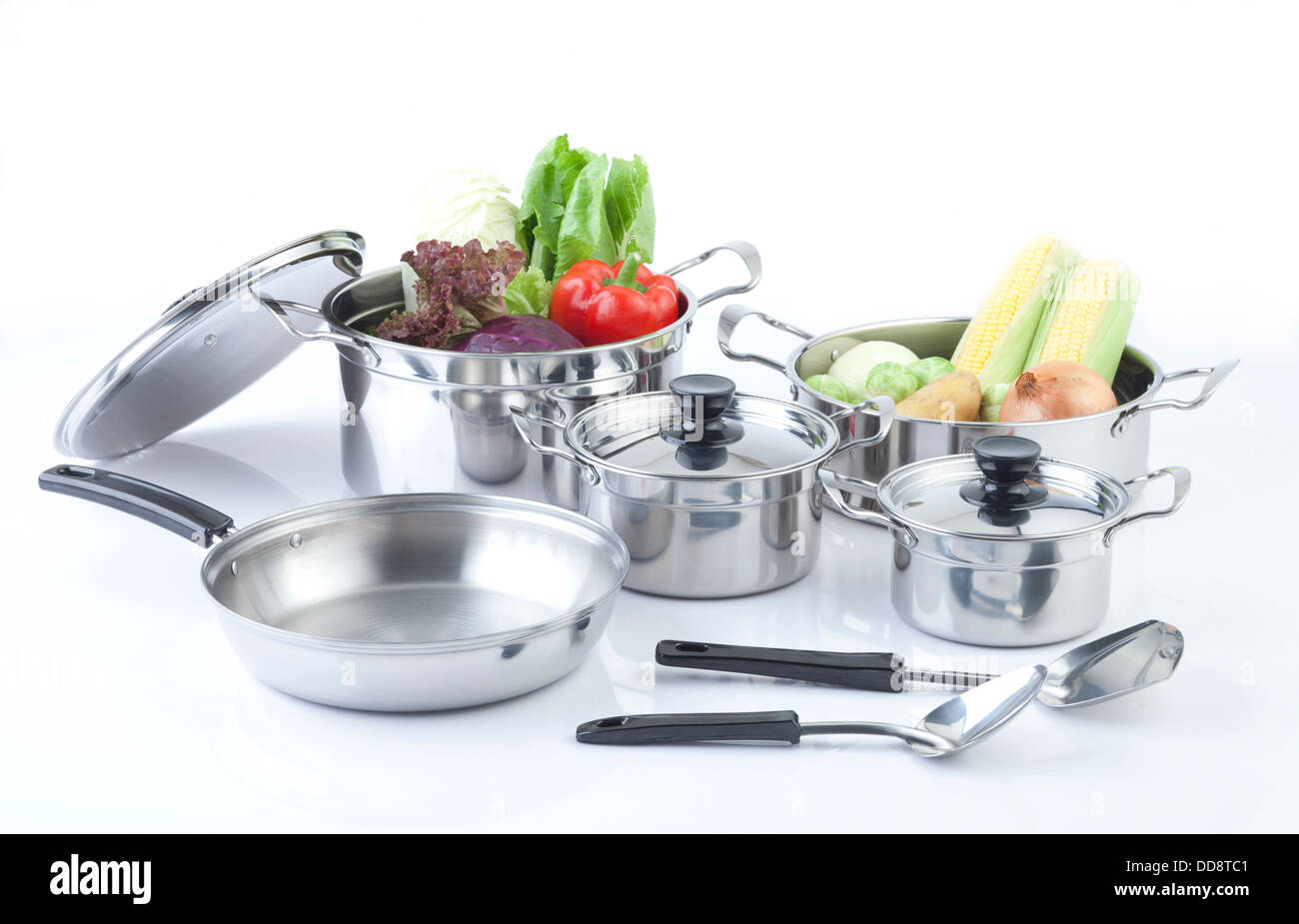Set of stainless pots with lids and vegetables Stock Photo