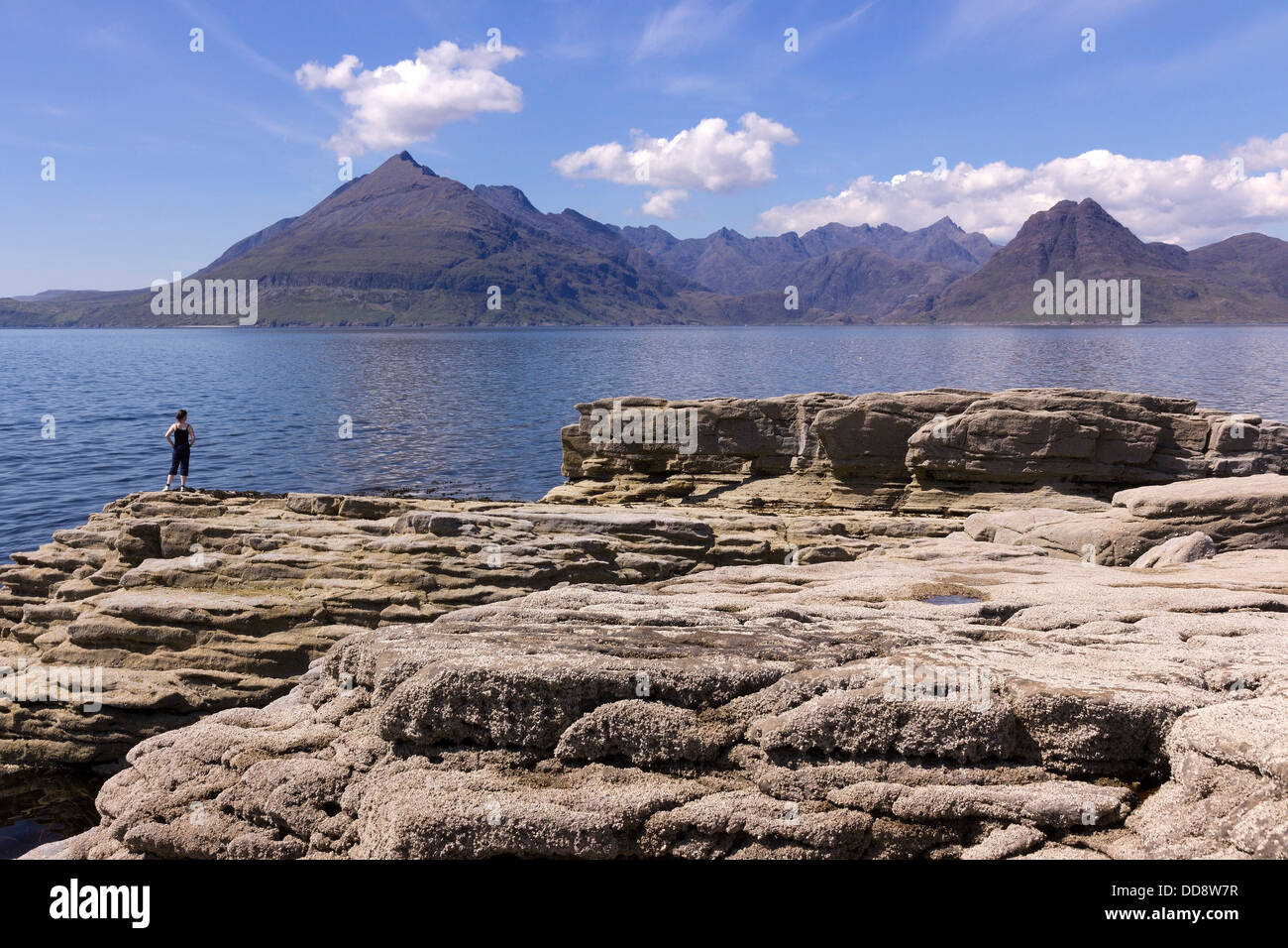 Female holidaymaker admiring view from Elgol over Sea Loch Scavaig to the Black Cuillin mountains, Isle of Skye, Scotland, UK Stock Photo