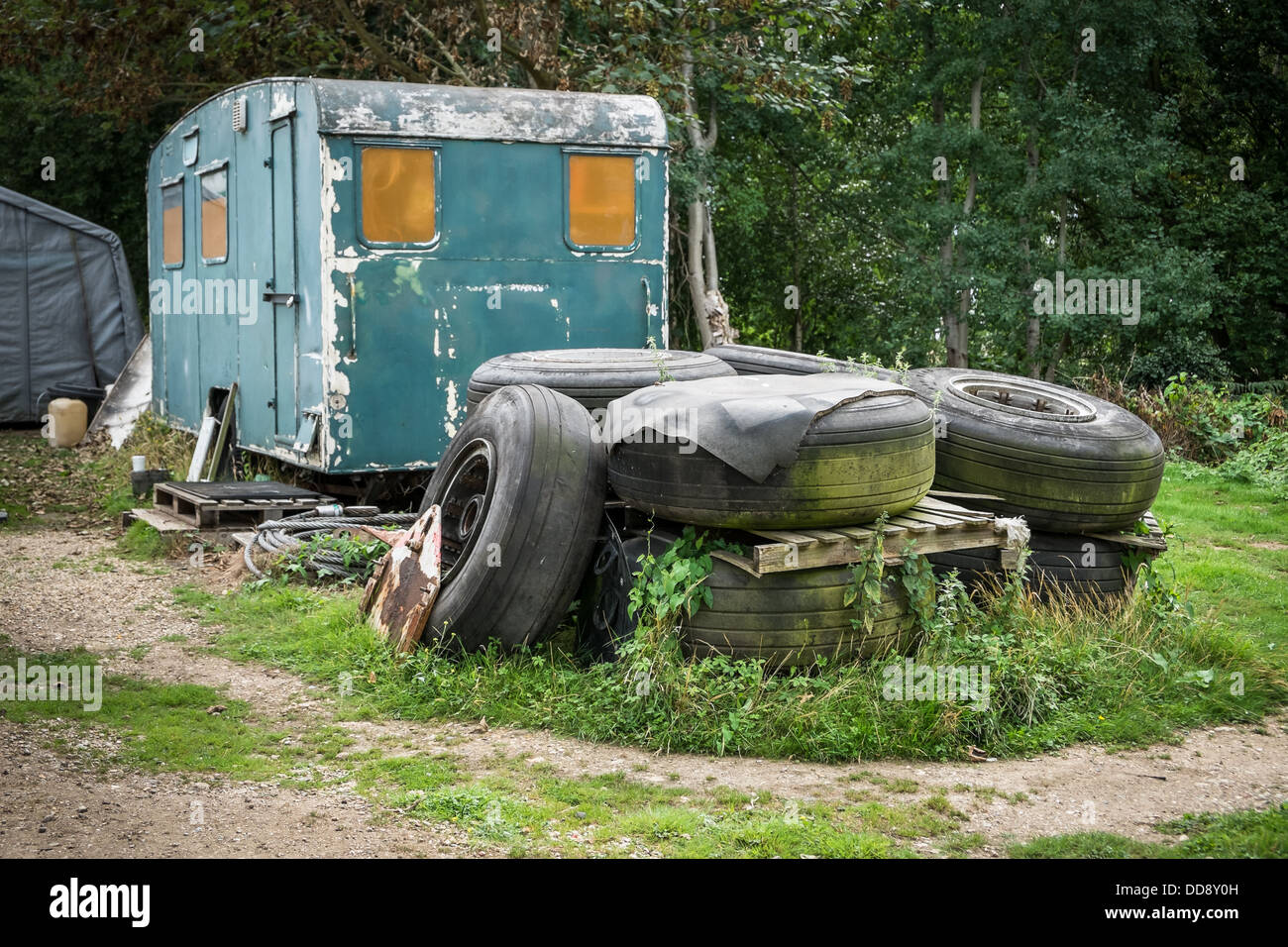 A pile of old tires in front of an abandoned derelict caravan Stock Photo