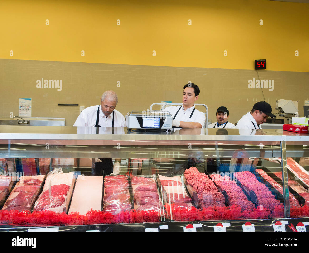 Butchers at meat counter of grocery store Stock Photo