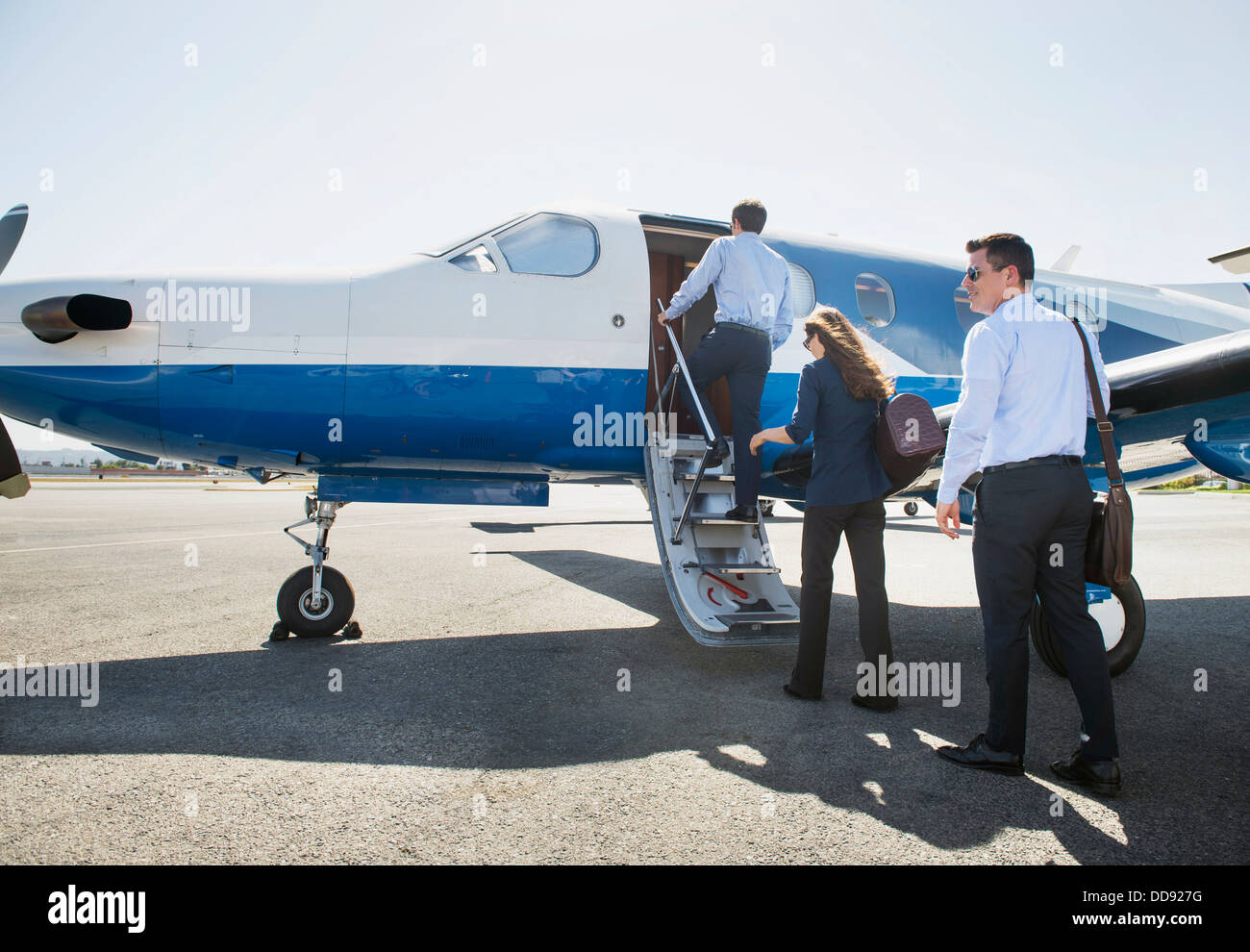 Business people boarding airplane on runway Stock Photo