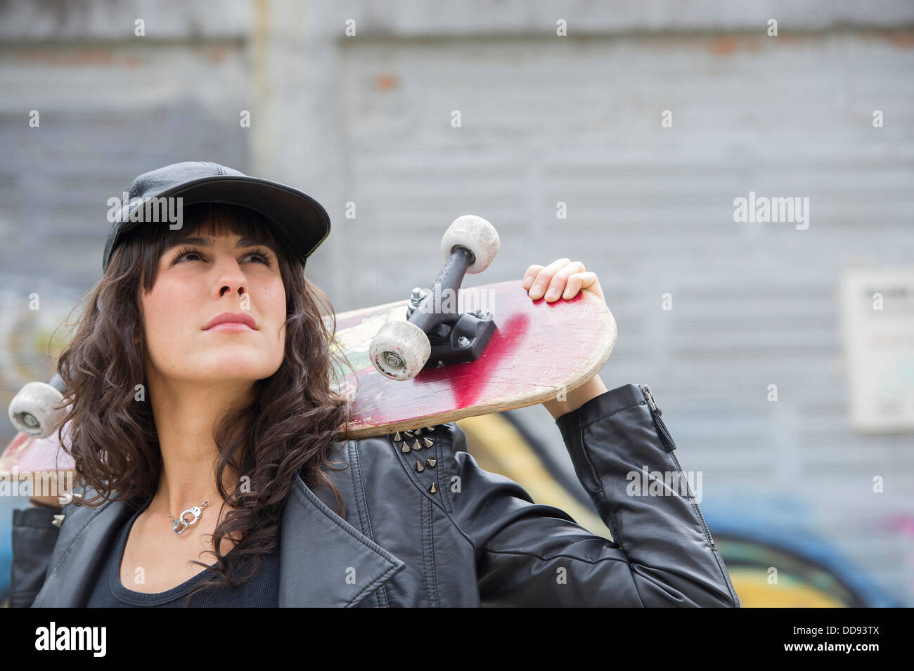 Hispanic woman holding skateboard outdoors Stock Photo