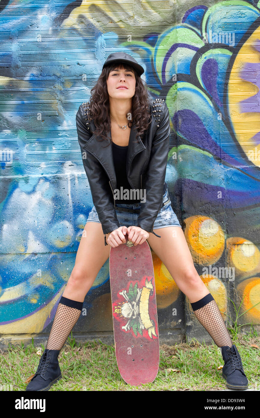 Hispanic woman with skateboard outdoors Stock Photo