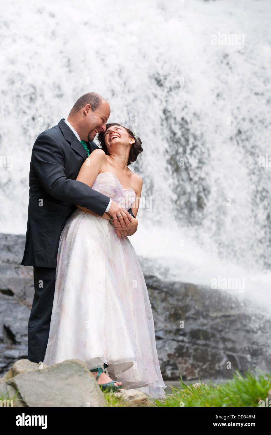 Hispanic newlyweds hugging by waterfall Stock Photo