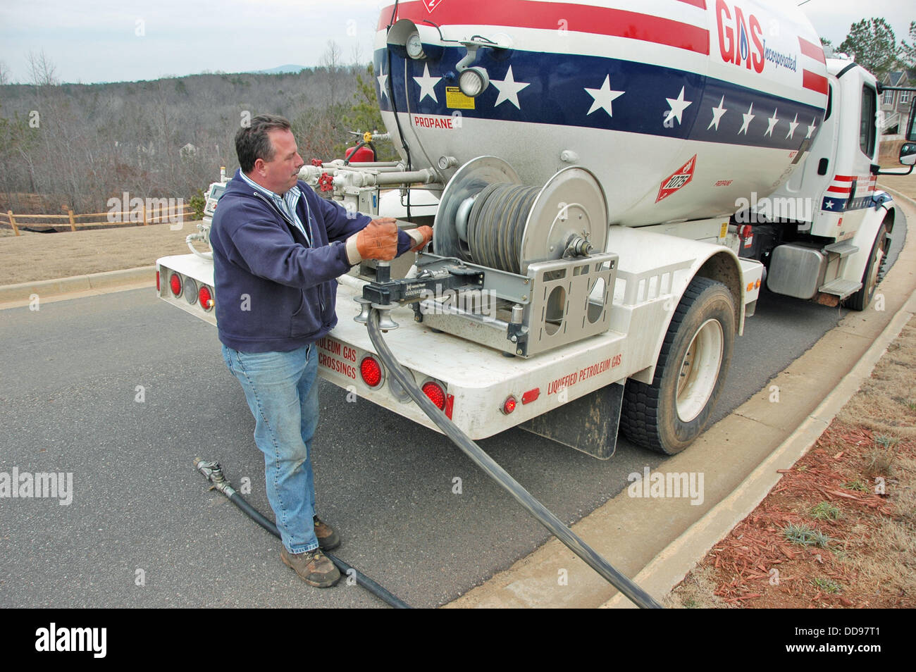 Propane delivery man putting gas into underground tank for family home
