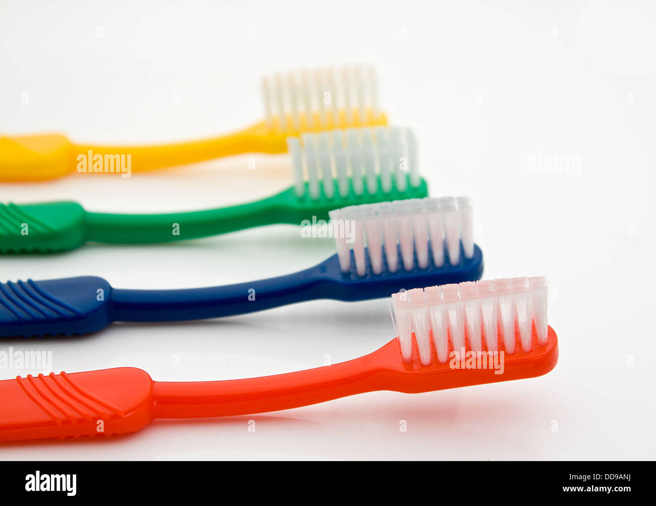 Detail of a row of different colored toothbrushes with the front one in selective focus good for dentists Stock Photo