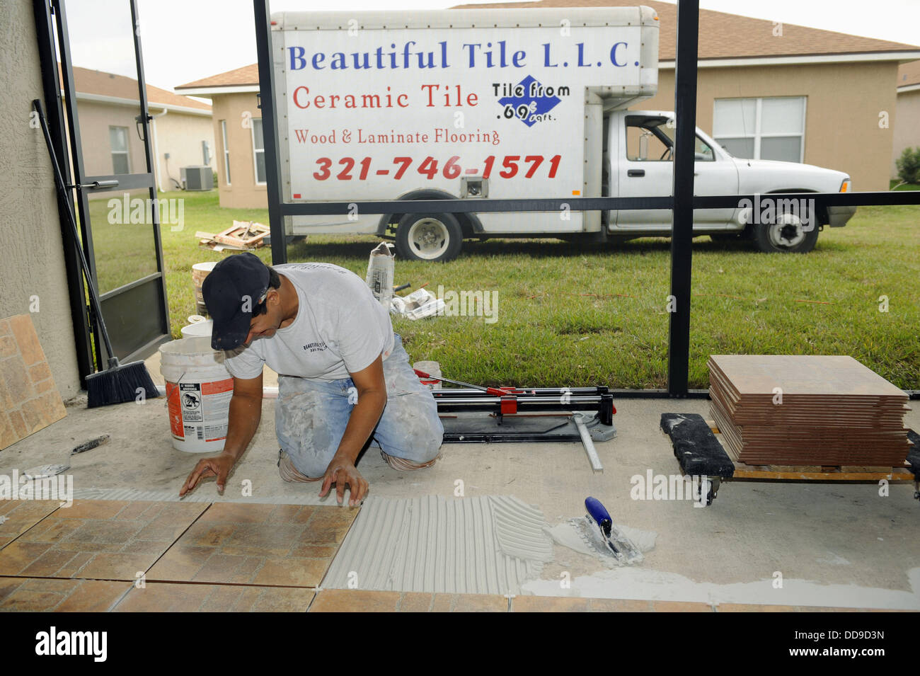 Male Hispanic Lays Ceramic Tile on Cement Floor in Patio Lanai Stock